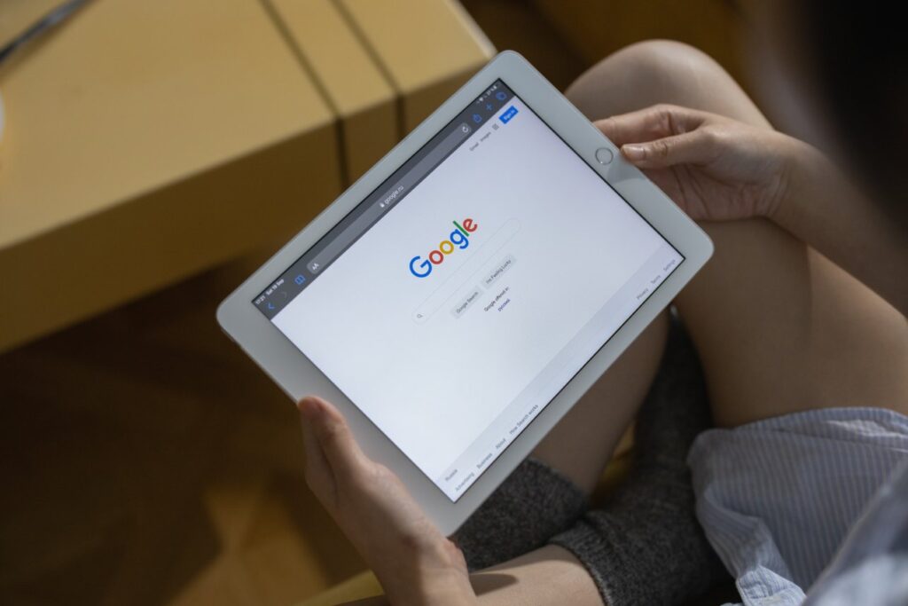 Woman holding tablet in lap showing Google search screen